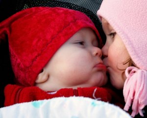 girl kissing baby red
