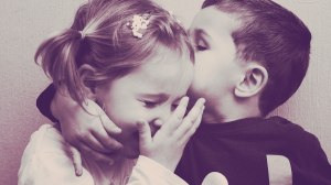 happy girl kissing boy ear