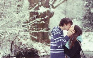 kissing while snowing under the trees